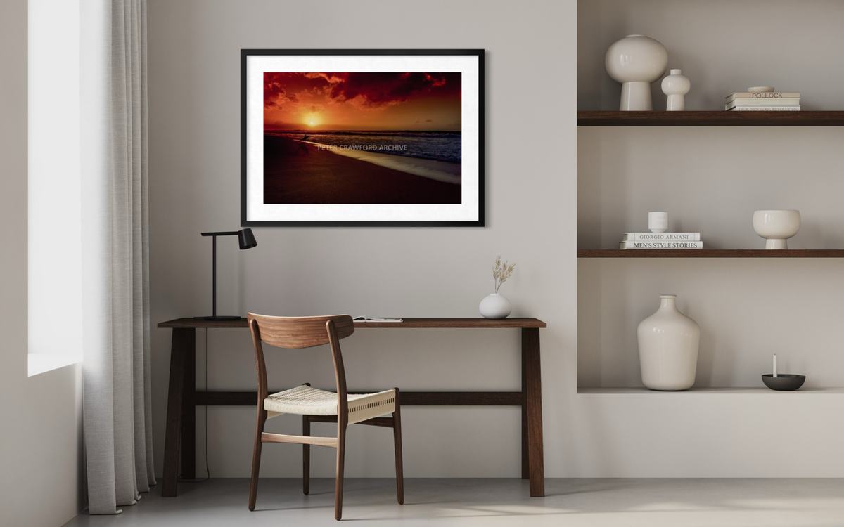 Sunset Favourite in a black frame with a white mat above a console table. Peter Crawford Archive.