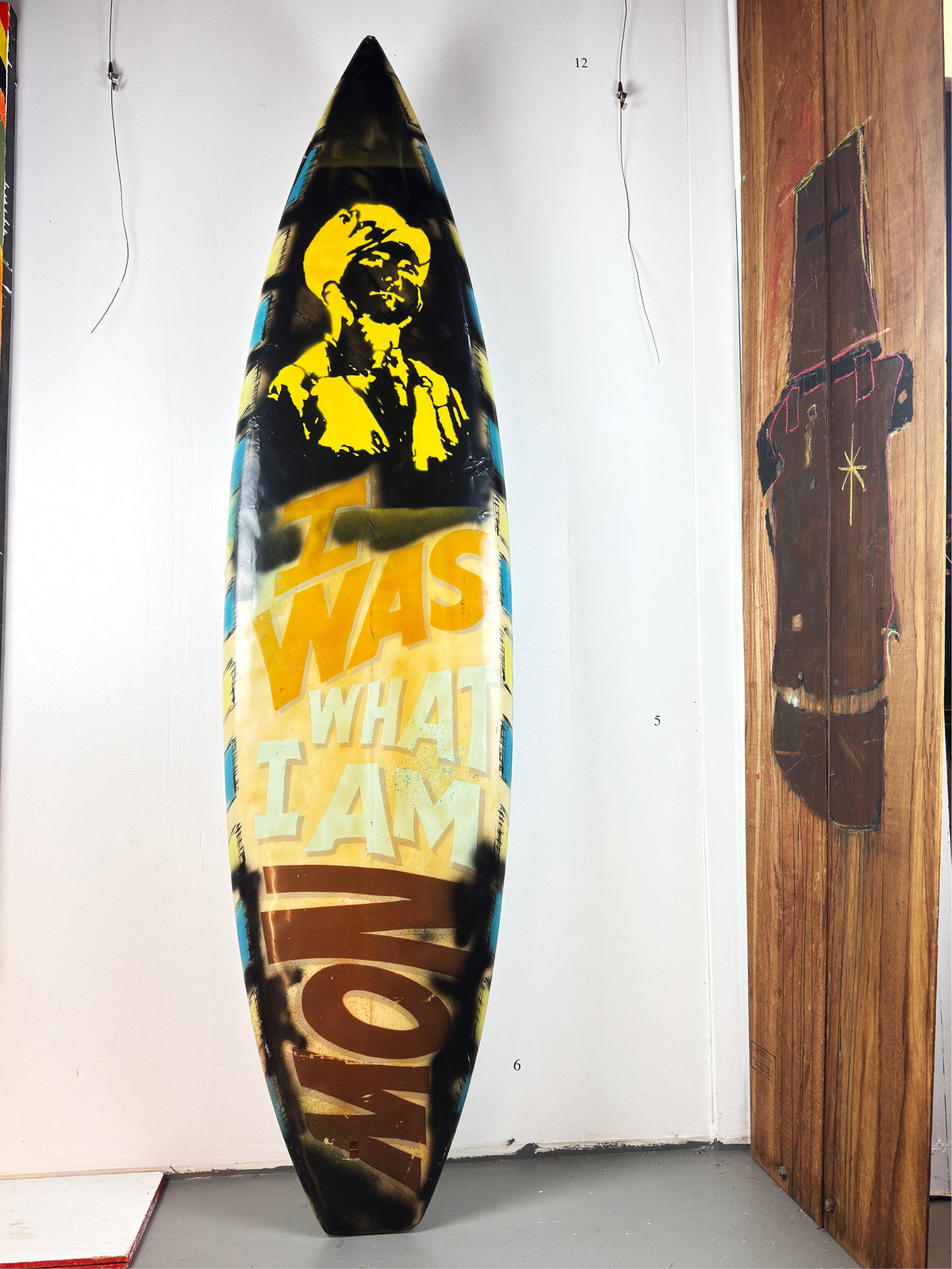 What I am Now Surfboard by David Bromley — lettered side standing in the gallery.