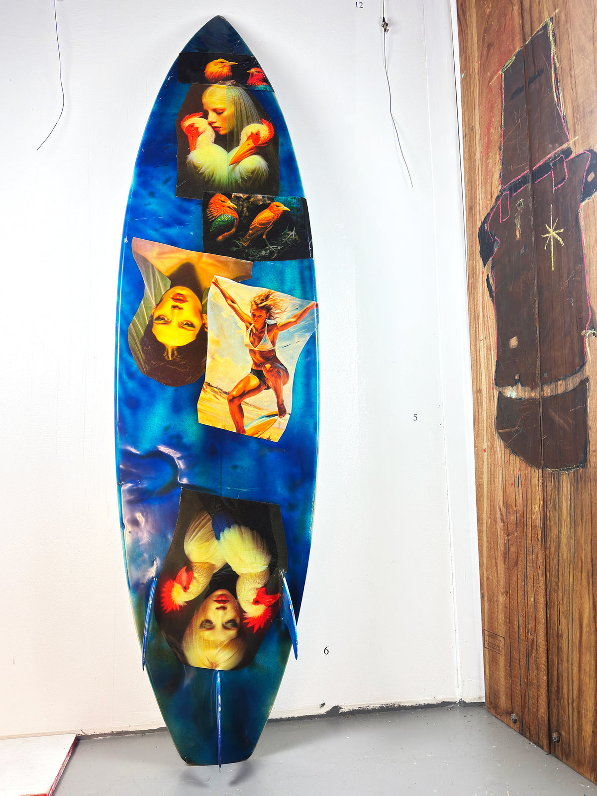 What I am Now Surfboard by David Bromley — blue figurative side standing in the gallery.