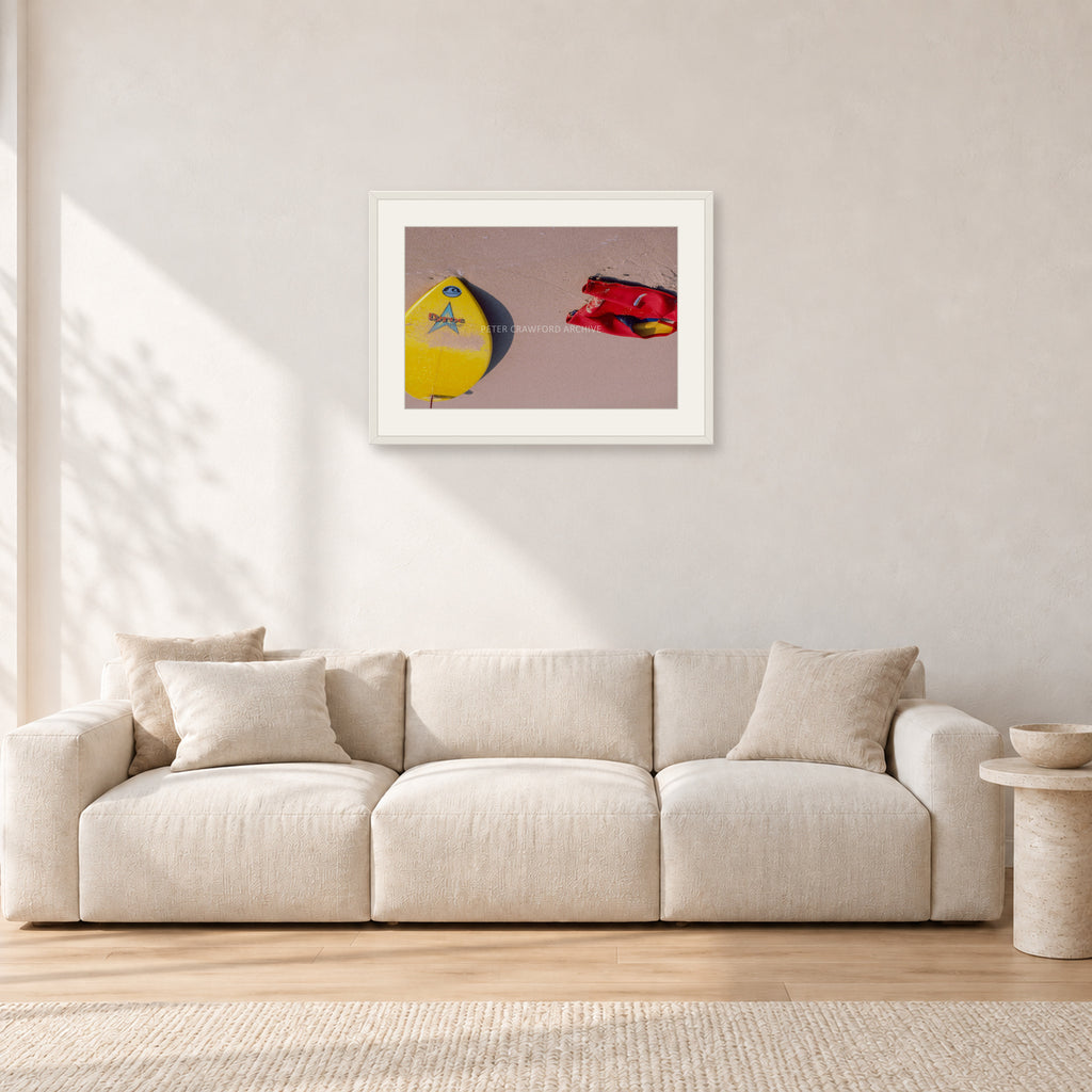 Bells Beach Overview, 1983 by Peter Crawford — 60 × 40 cm, white frame with white mat, shown in a light minimalist living room.