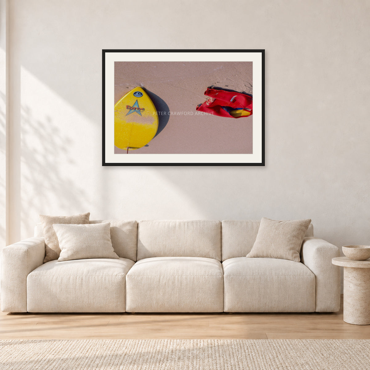 Bells Beach Overview, 1983 by Peter Crawford — 90 × 60 cm, black frame with white mat, shown in a light minimalist living room.