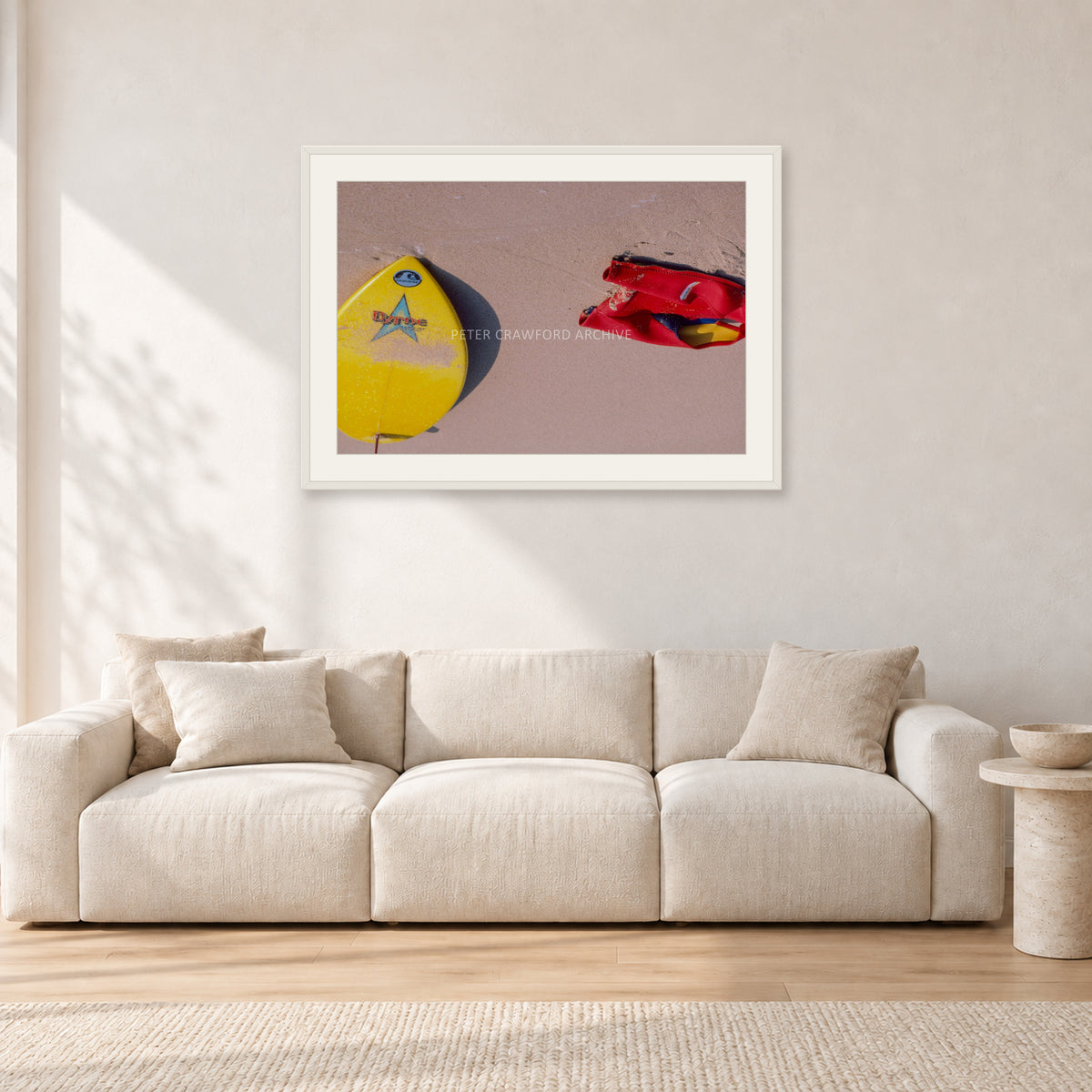 Bells Beach Overview, 1983 by Peter Crawford — 90 × 60 cm, white frame with white mat, shown in a light minimalist living room.