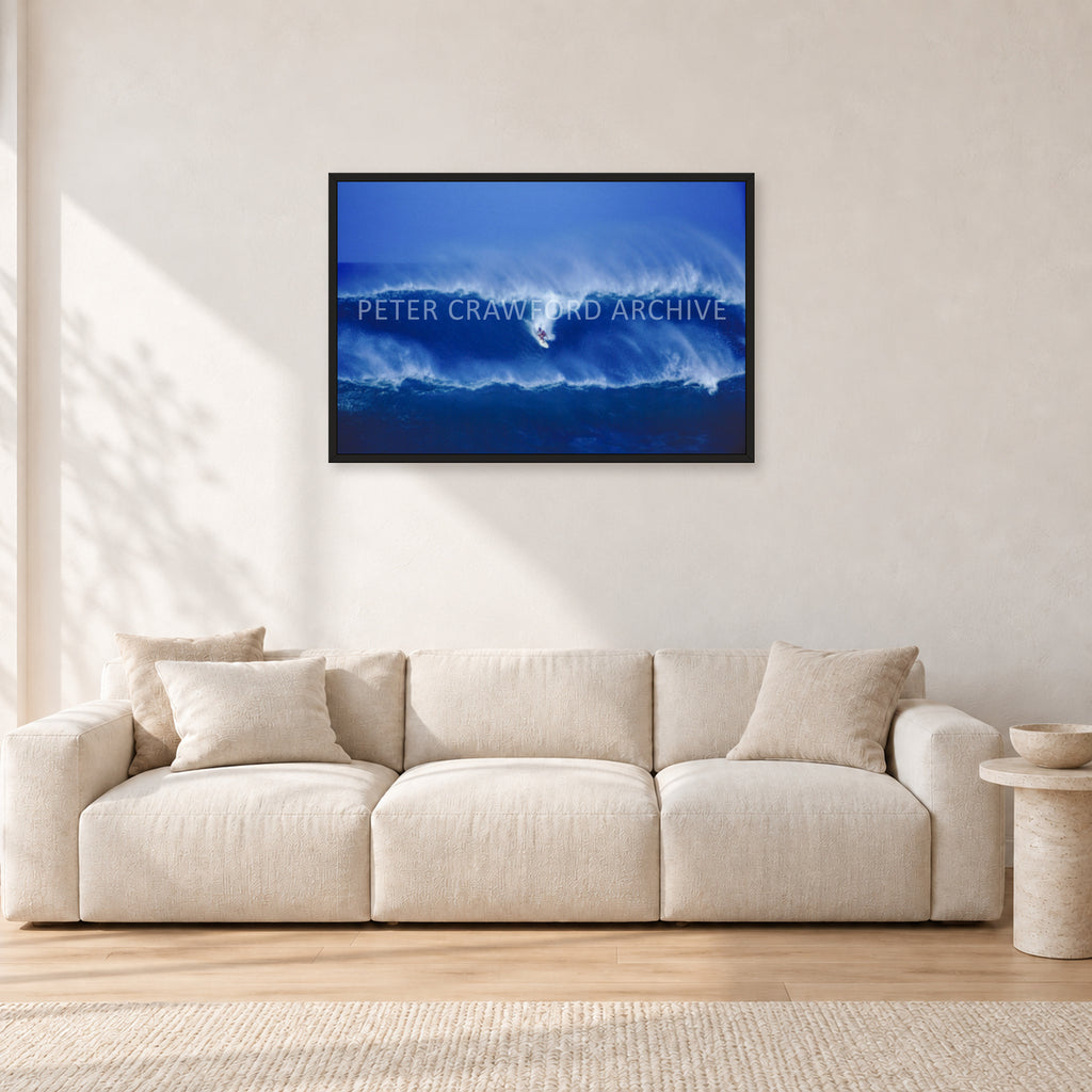 Big Sunset, Unknown Surfer by Peter Crawford — 90 × 60 cm, black frame, shown in a light minimalist living room.