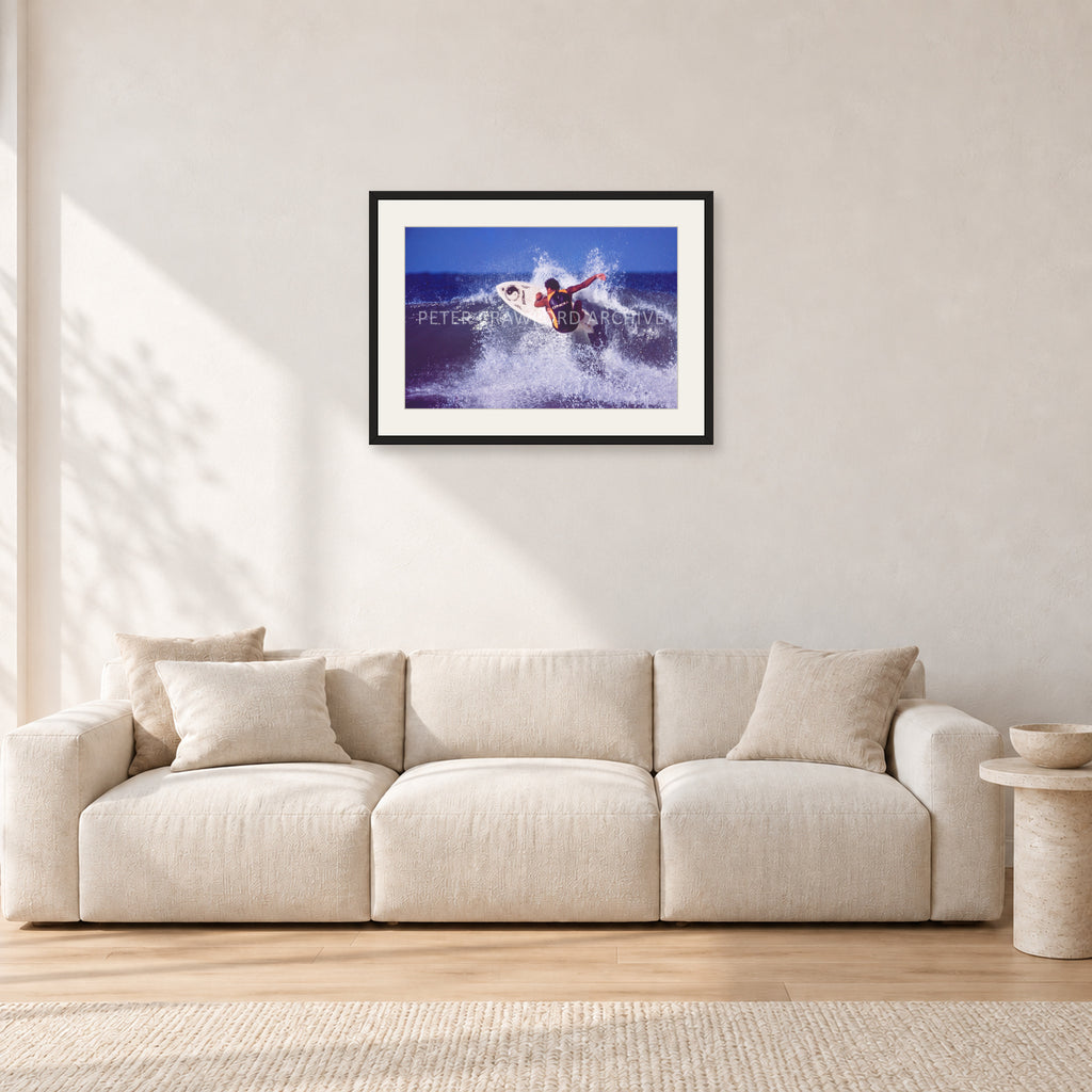 Dane Kealoha, Off The Wall 1977 by Peter Crawford — 60 × 40 cm, black frame with white mat, shown in a light minimalist living room.