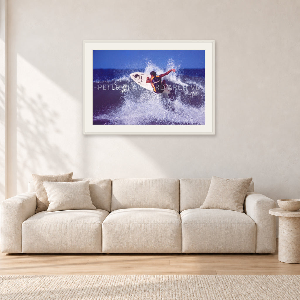 Dane Kealoha, Off The Wall 1977 by Peter Crawford — 90 × 60 cm, white frame with white mat, shown in a light minimalist living room.