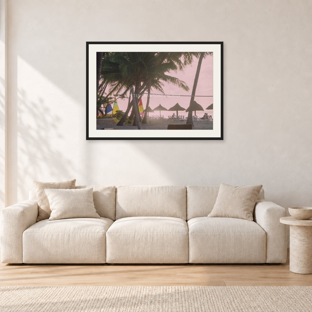 Fiji Sunset I by Peter Crawford — 90 × 60 cm, black frame with white mat, shown in a light minimalist living room.