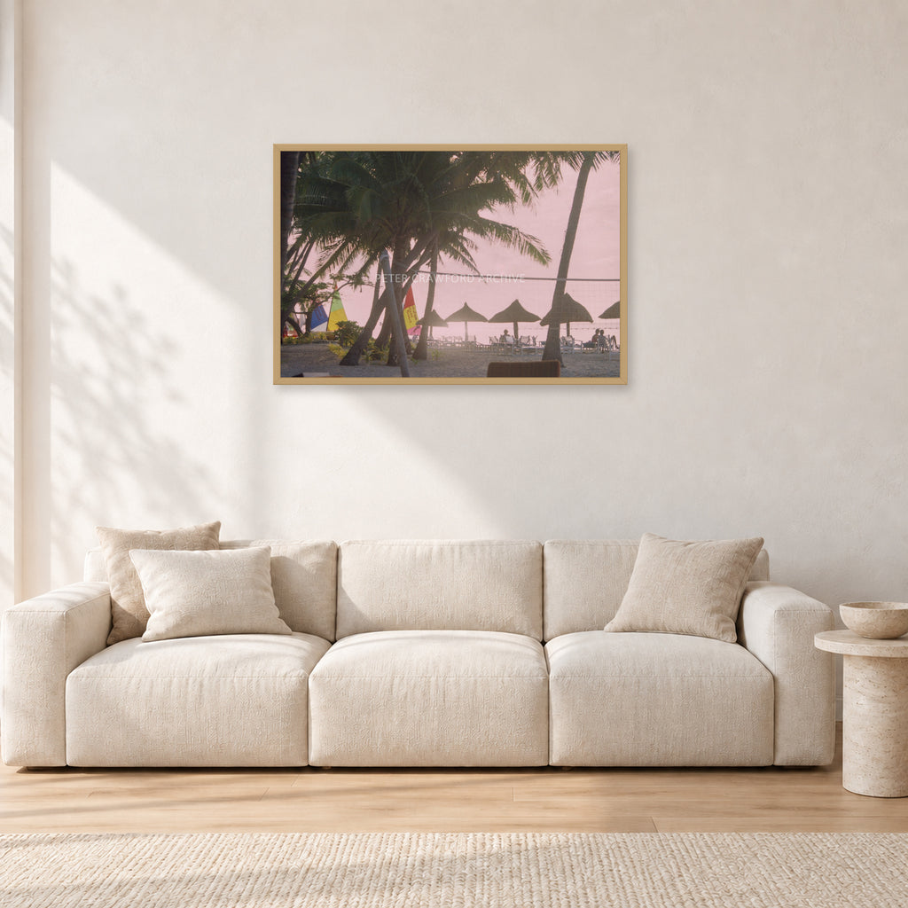 Fiji Sunset I by Peter Crawford — 90 × 60 cm, hayseed frame, shown in a light minimalist living room.