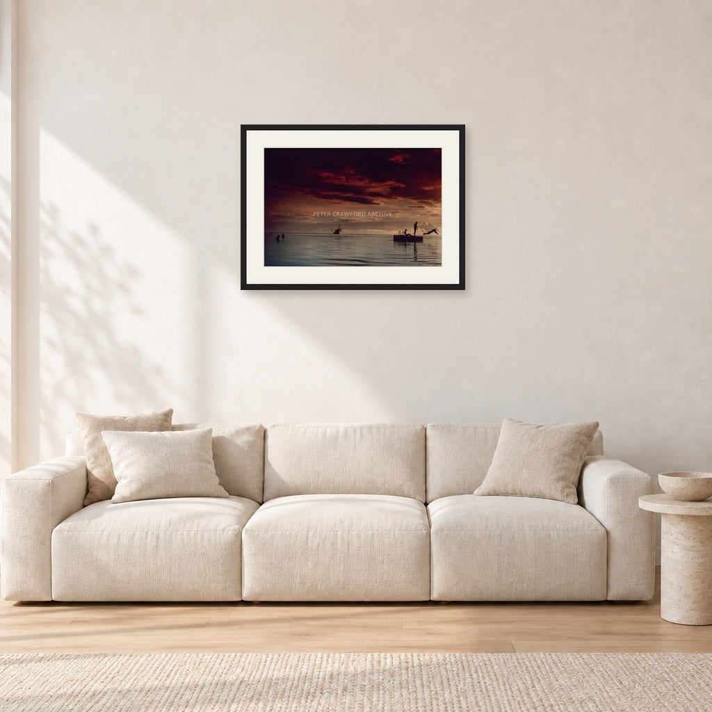 Fiji Sunset II by Peter Crawford — 60 × 40 cm, black frame with white mat, shown in a light minimalist living room.