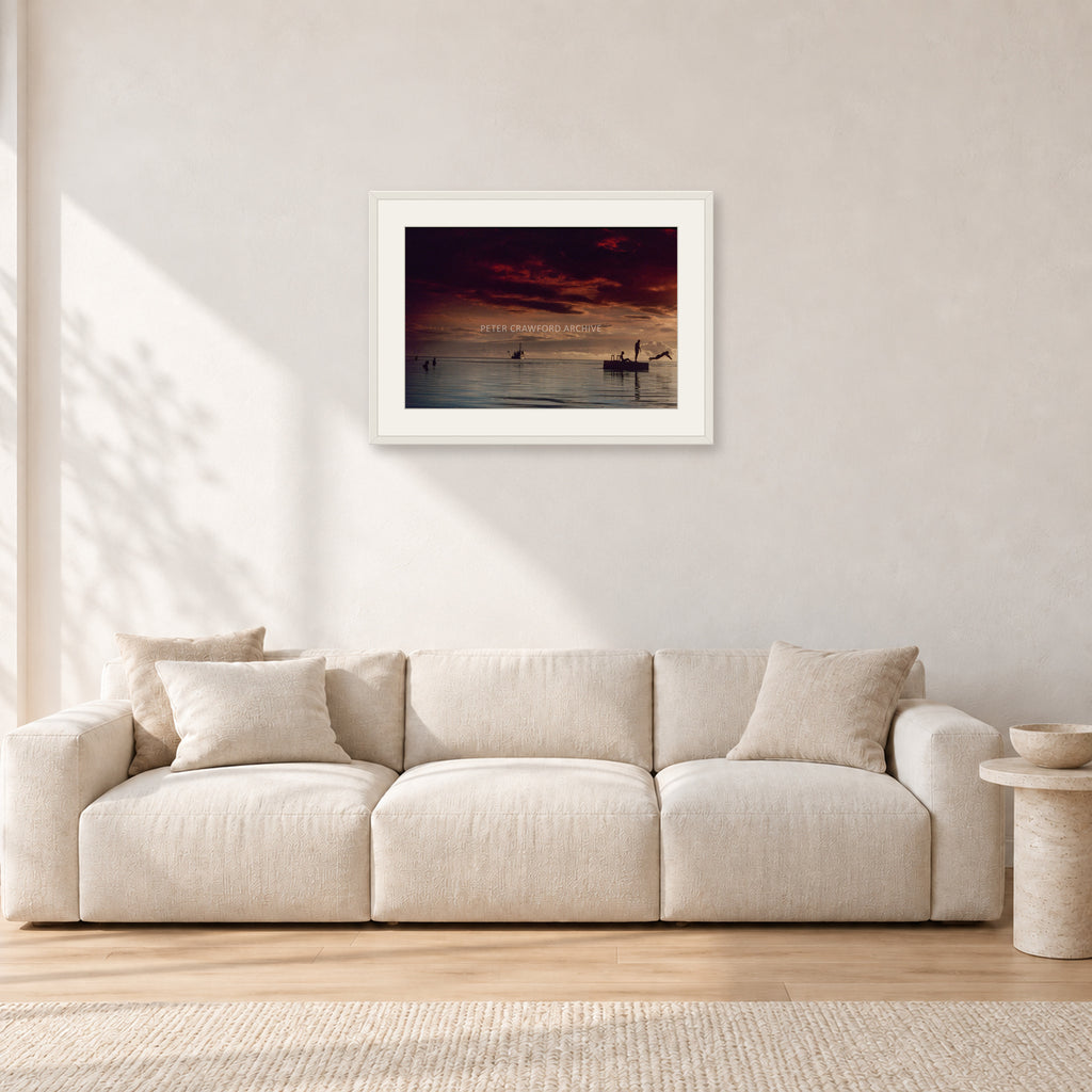 Fiji Sunset II by Peter Crawford — 60 × 40 cm, white frame with white mat, shown in a light minimalist living room.