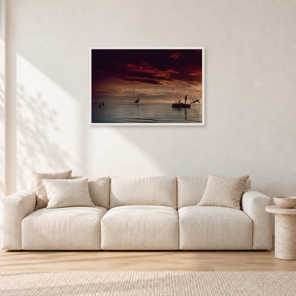 Fiji Sunset II by Peter Crawford — 90 × 60 cm, white frame, shown in a light minimalist living room.