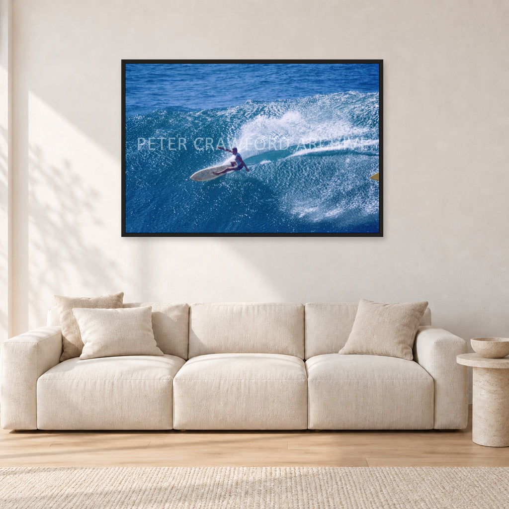 Honolua Bay, No Leash by Peter Crawford — 120 × 80 cm, black frame, shown in a light minimalist living room.