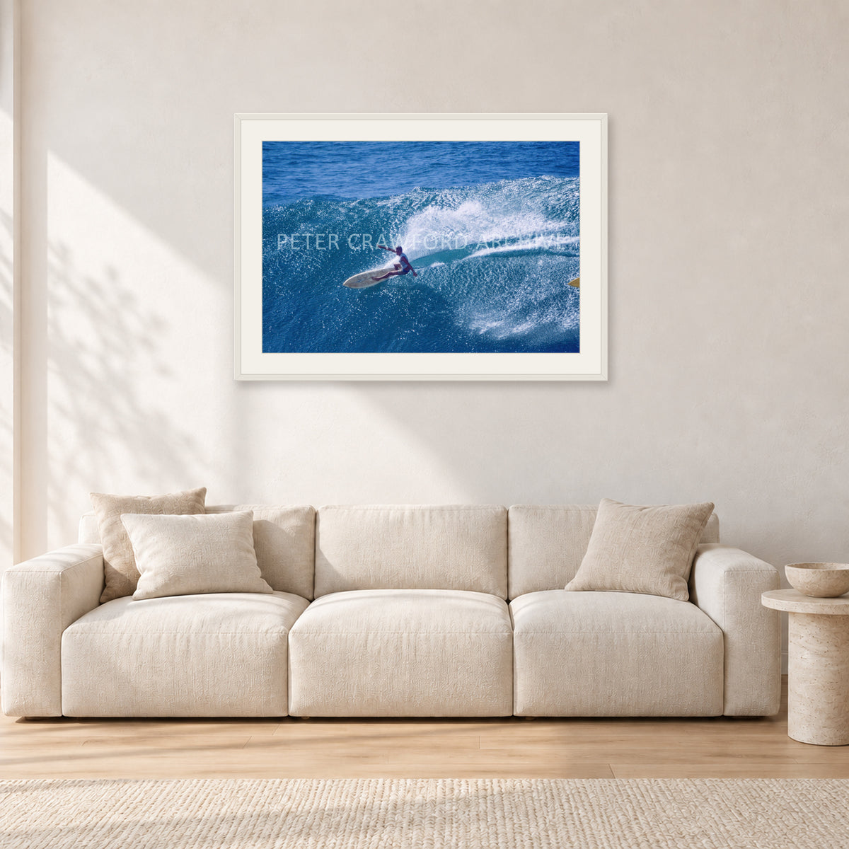Honolua Bay, No Leash by Peter Crawford — 90 × 60 cm, white frame with white mat, shown in a light minimalist living room.