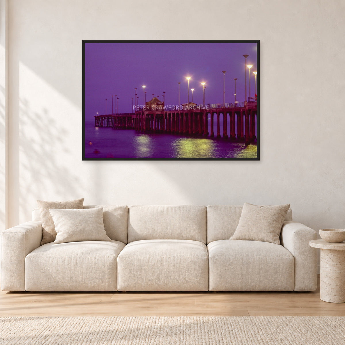Huntington Pier by Peter Crawford — 120 × 80 cm, black frame, shown in a light minimalist living room.