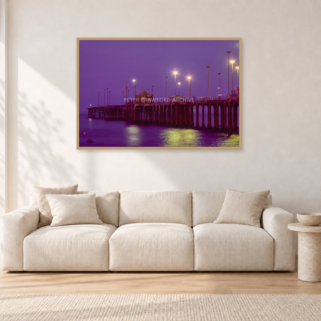 Huntington Pier by Peter Crawford — 120 × 80 cm, hayseed frame, shown in a light minimalist living room.
