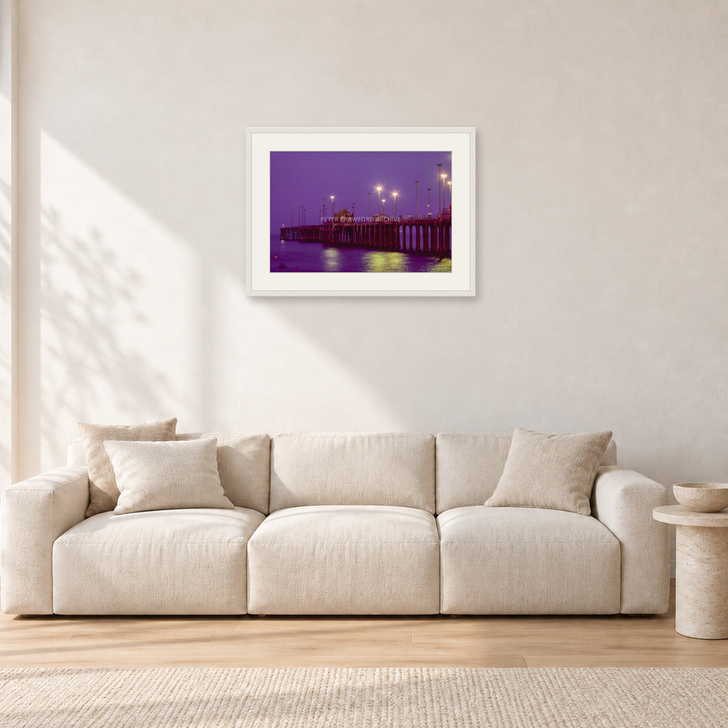 Huntington Pier by Peter Crawford — 60 × 40 cm, white frame with white mat, shown in a light minimalist living room.