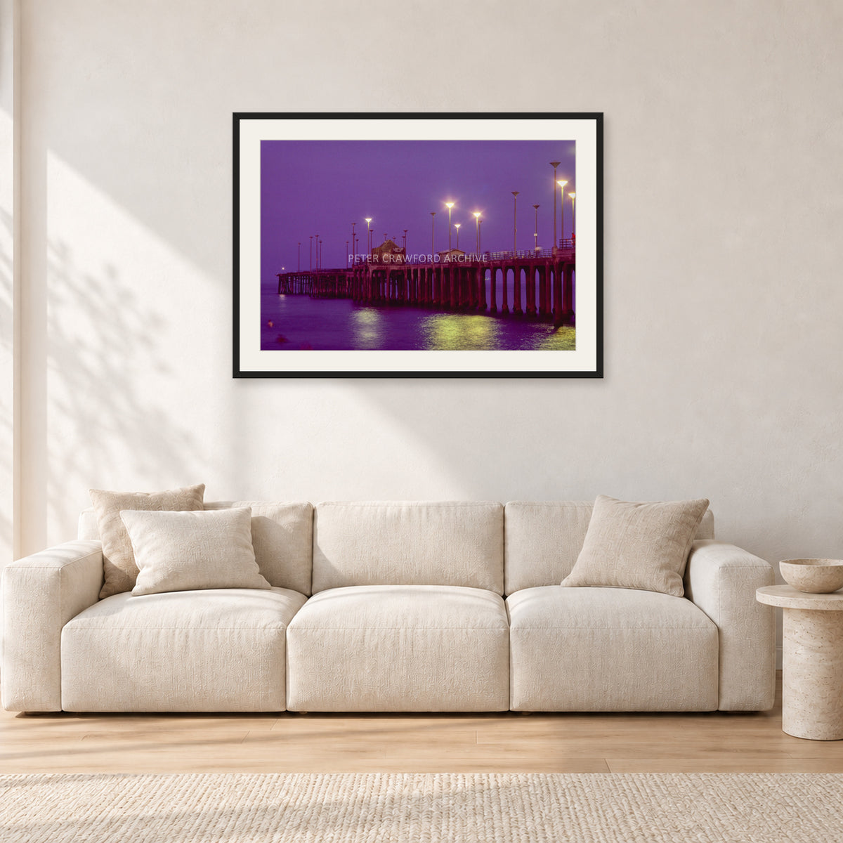 Huntington Pier by Peter Crawford — 90 × 60 cm, black frame with white mat, shown in a light minimalist living room.