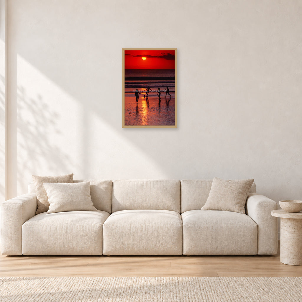 Indonesian Sunset Kids by Peter Crawford — 40 × 60 cm, hayseed frame, shown in a light minimalist living room.