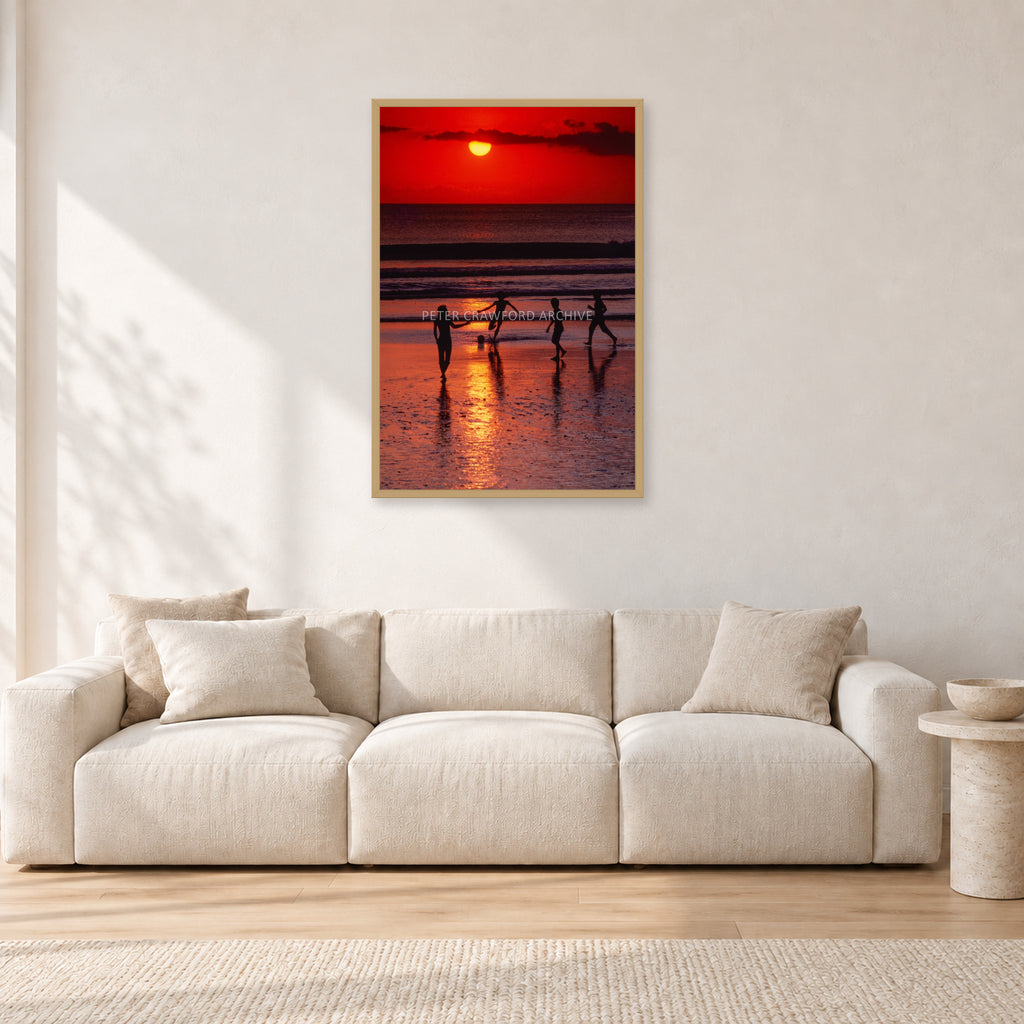 Indonesian Sunset Kids by Peter Crawford — 60 × 90 cm, hayseed frame, shown in a light minimalist living room.
