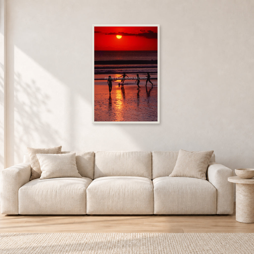 Indonesian Sunset Kids by Peter Crawford — 60 × 90 cm, white frame, shown in a light minimalist living room.
