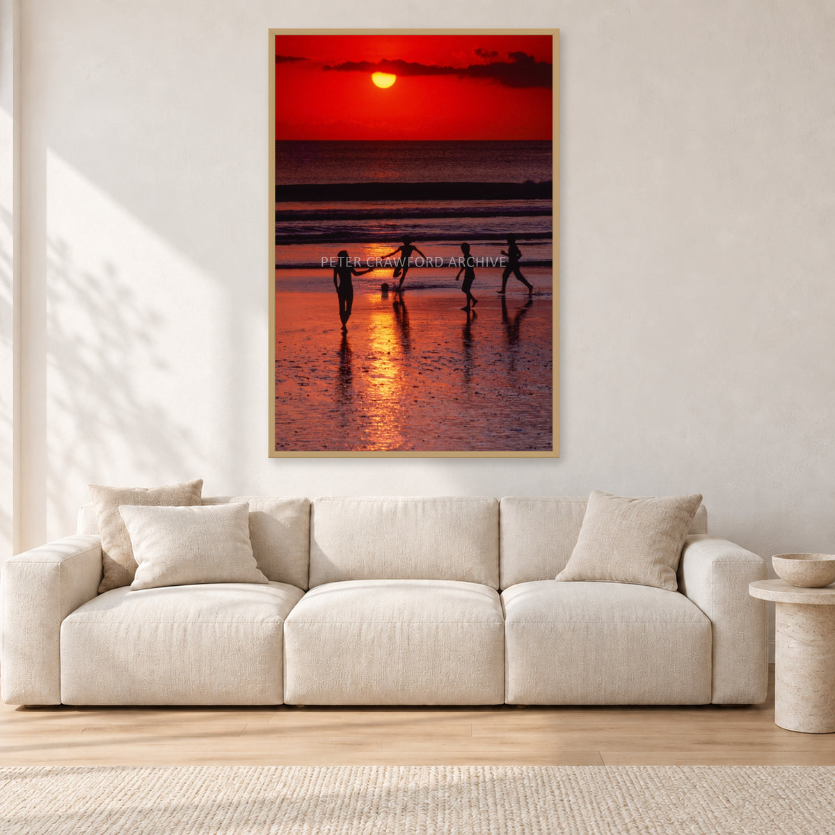 Indonesian Sunset Kids by Peter Crawford — 80 × 120 cm, hayseed frame, shown in a light minimalist living room.