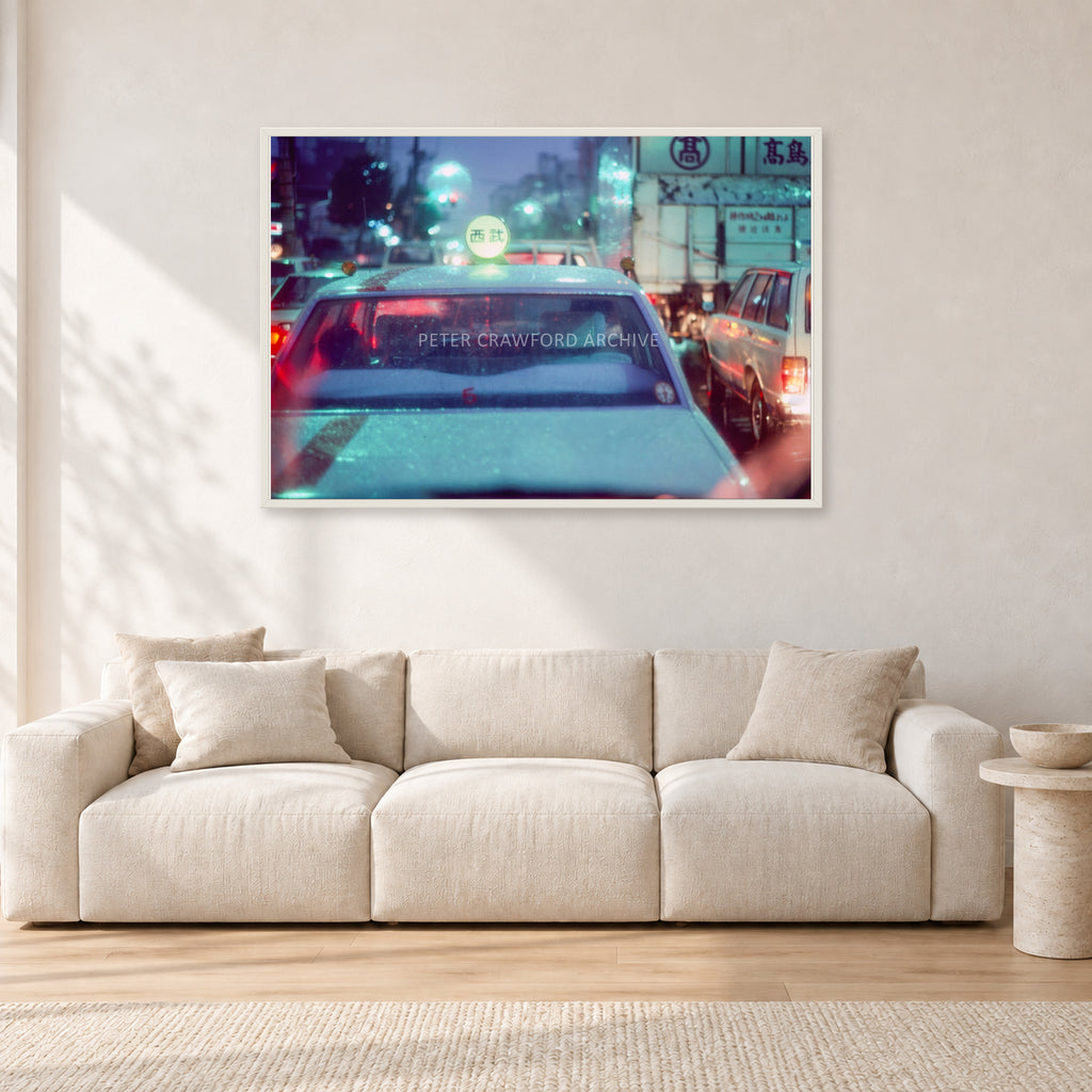 Japan City Lights by Peter Crawford — 120 × 80 cm, white frame, shown in a light minimalist living room.