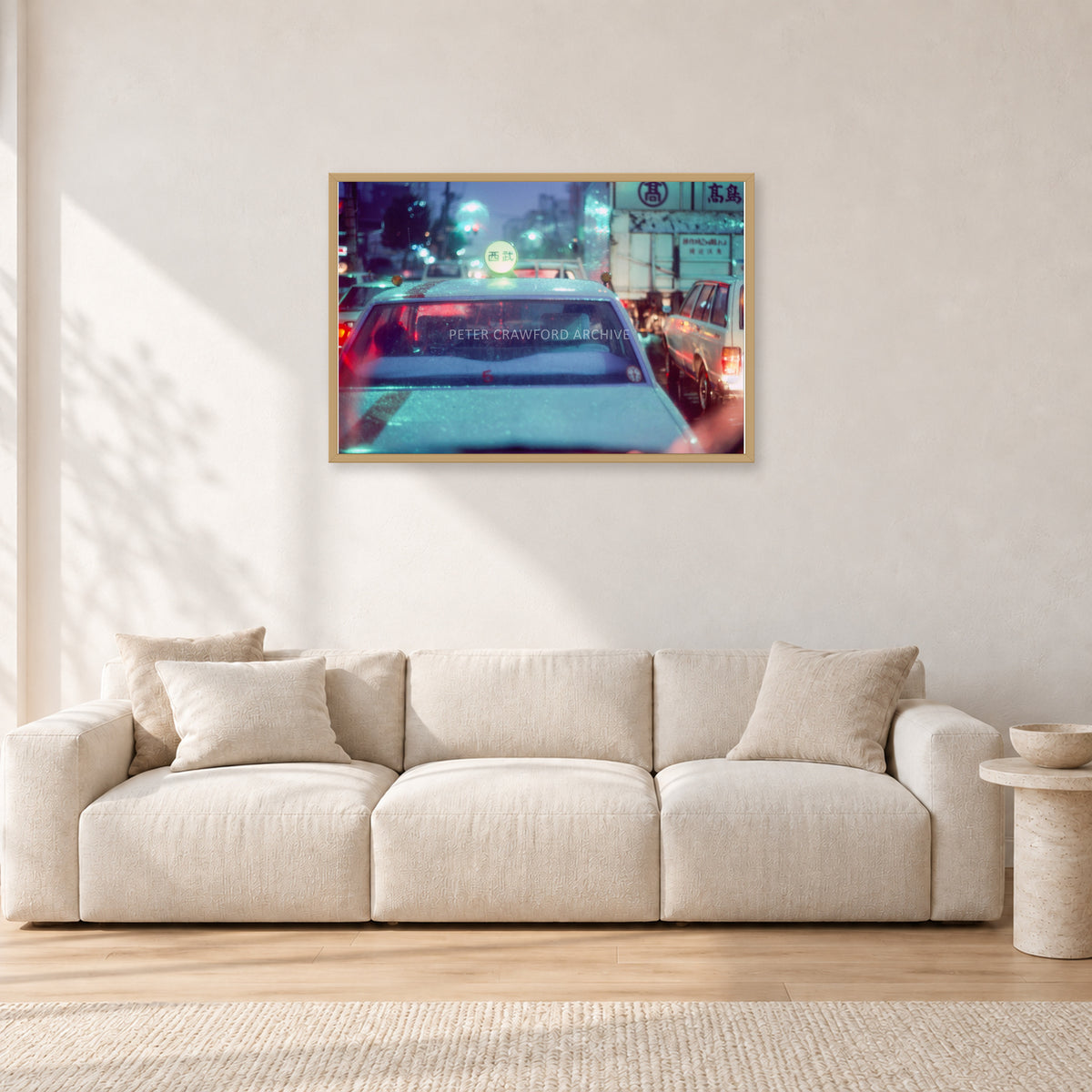Japan City Lights by Peter Crawford — 90 × 60 cm, hayseed frame, shown in a light minimalist living room.