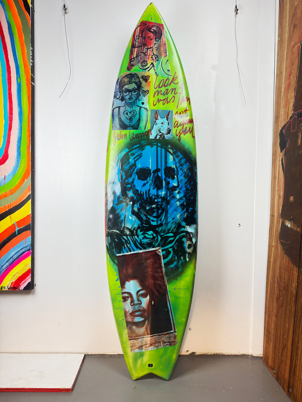 Blue Skulls Surfboard by David Bromley — blue skull side standing in the gallery.