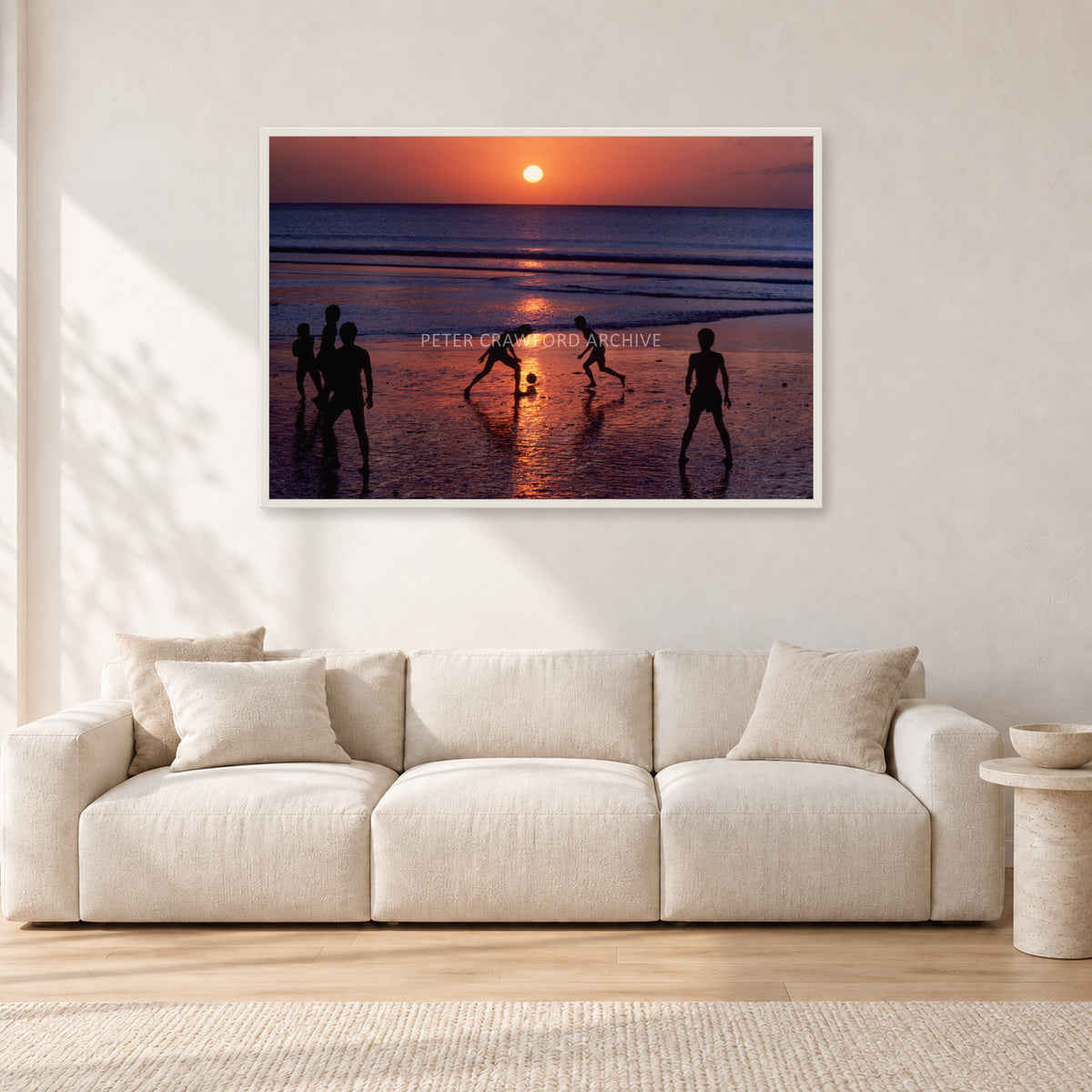 Kuta Kids Soccer, 1979 by Peter Crawford — 120 × 80 cm, white frame, shown in a light minimalist living room.