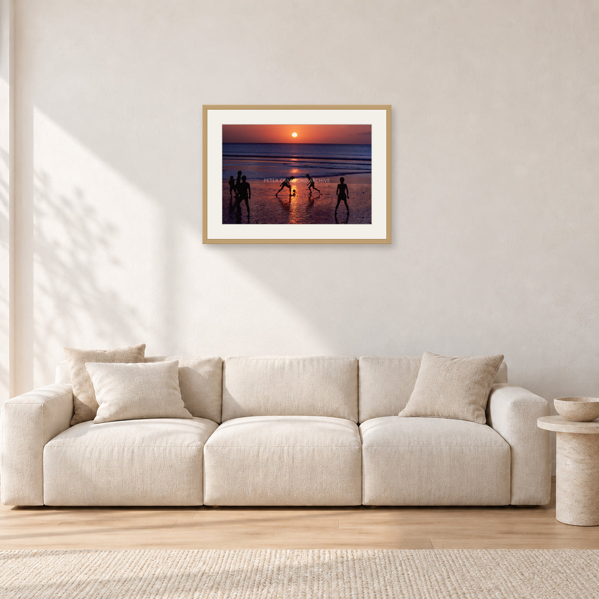 Kuta Kids Soccer, 1979 by Peter Crawford — 60 × 40 cm, hayseed frame with white mat, shown in a light minimalist living room.