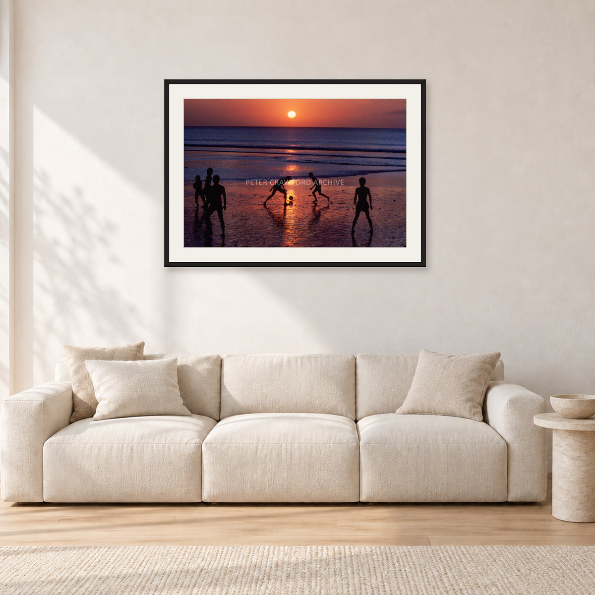 Kuta Kids Soccer, 1979 by Peter Crawford — 90 × 60 cm, black frame with white mat, shown in a light minimalist living room.