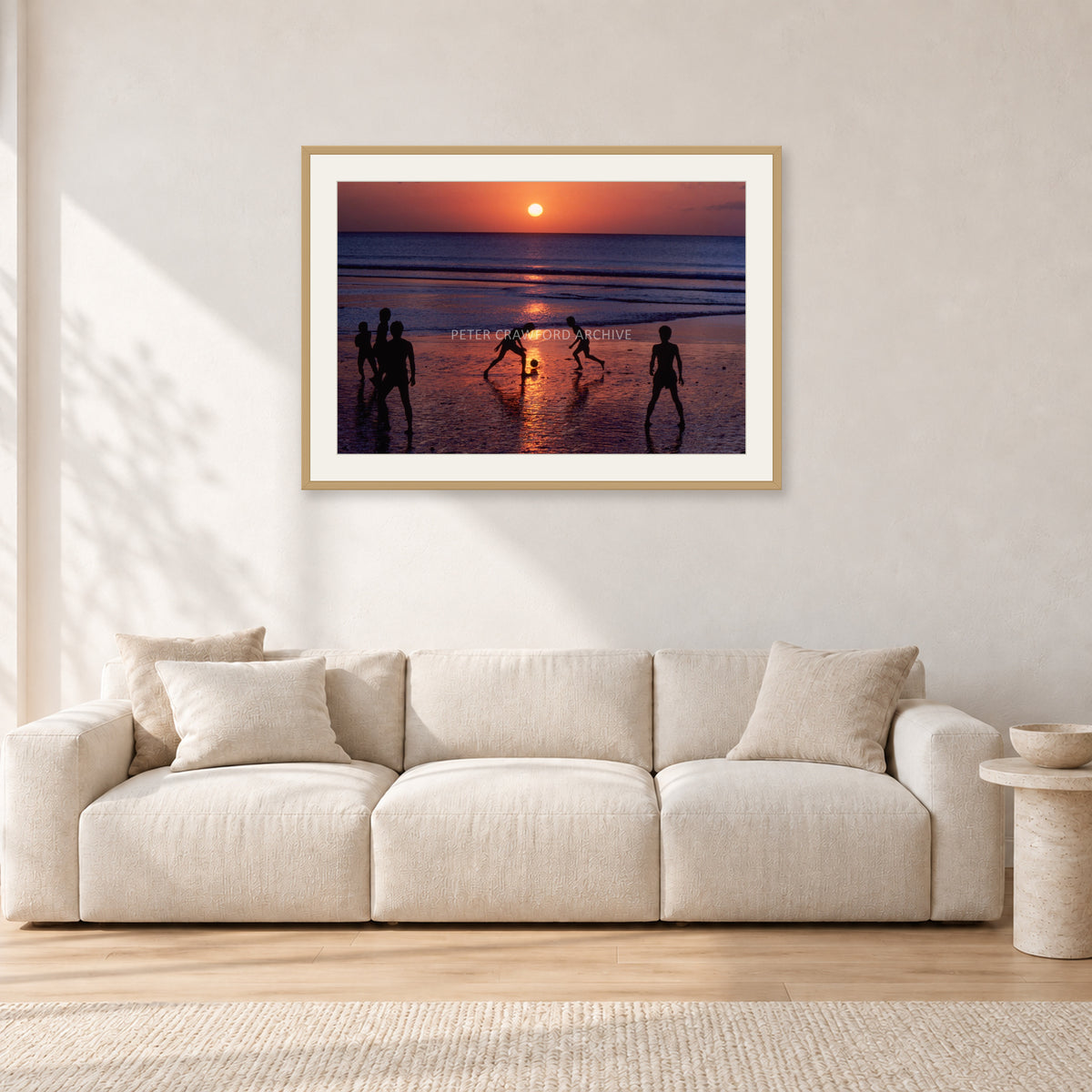 Kuta Kids Soccer, 1979 by Peter Crawford — 90 × 60 cm, hayseed frame with white mat, shown in a light minimalist living room.