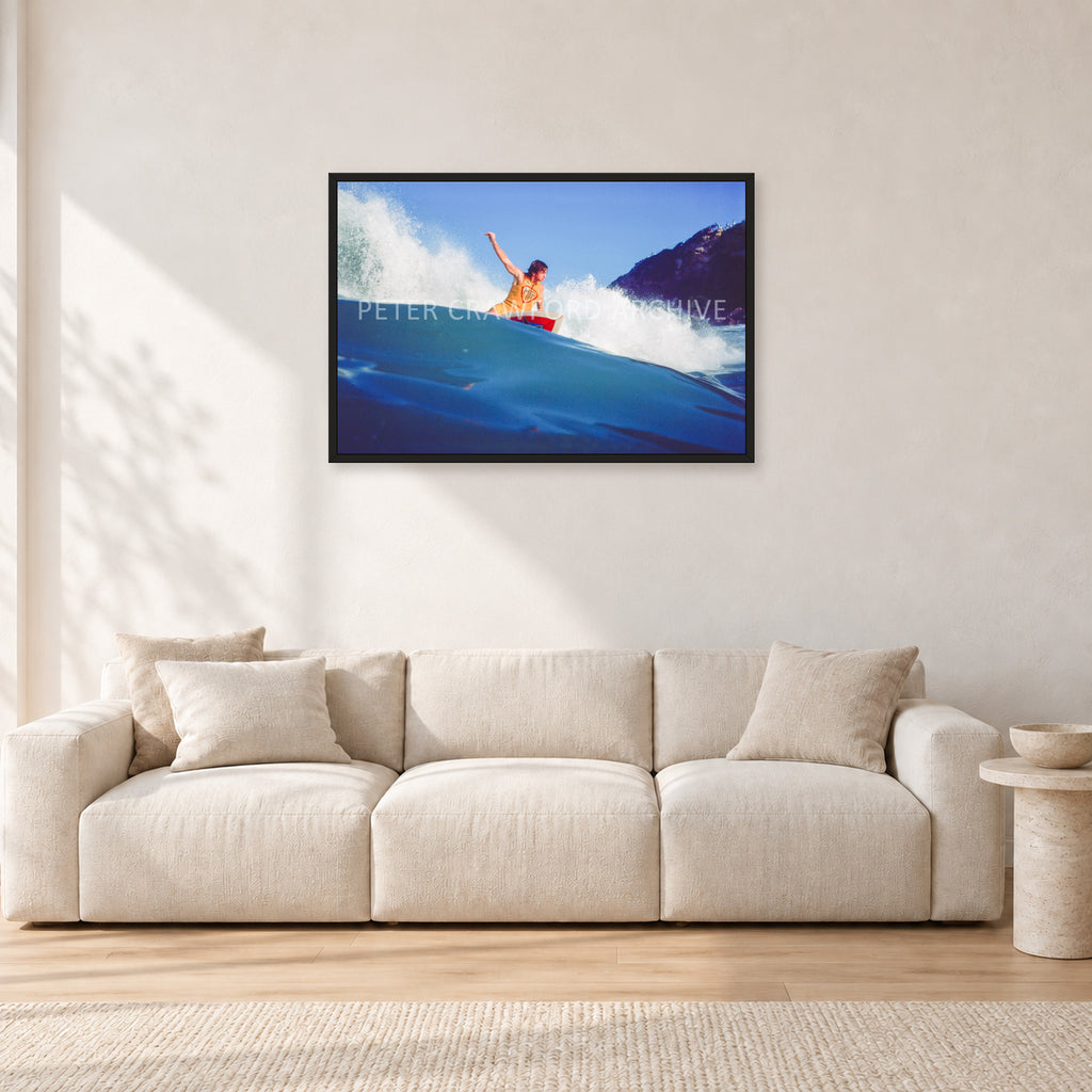 Mark Richards, Bells Beach 1979 by Peter Crawford — 90 × 60 cm, black frame, shown in a light minimalist living room.