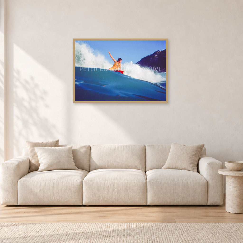 Mark Richards, Bells Beach 1979 by Peter Crawford — 90 × 60 cm, hayseed frame, shown in a light minimalist living room.