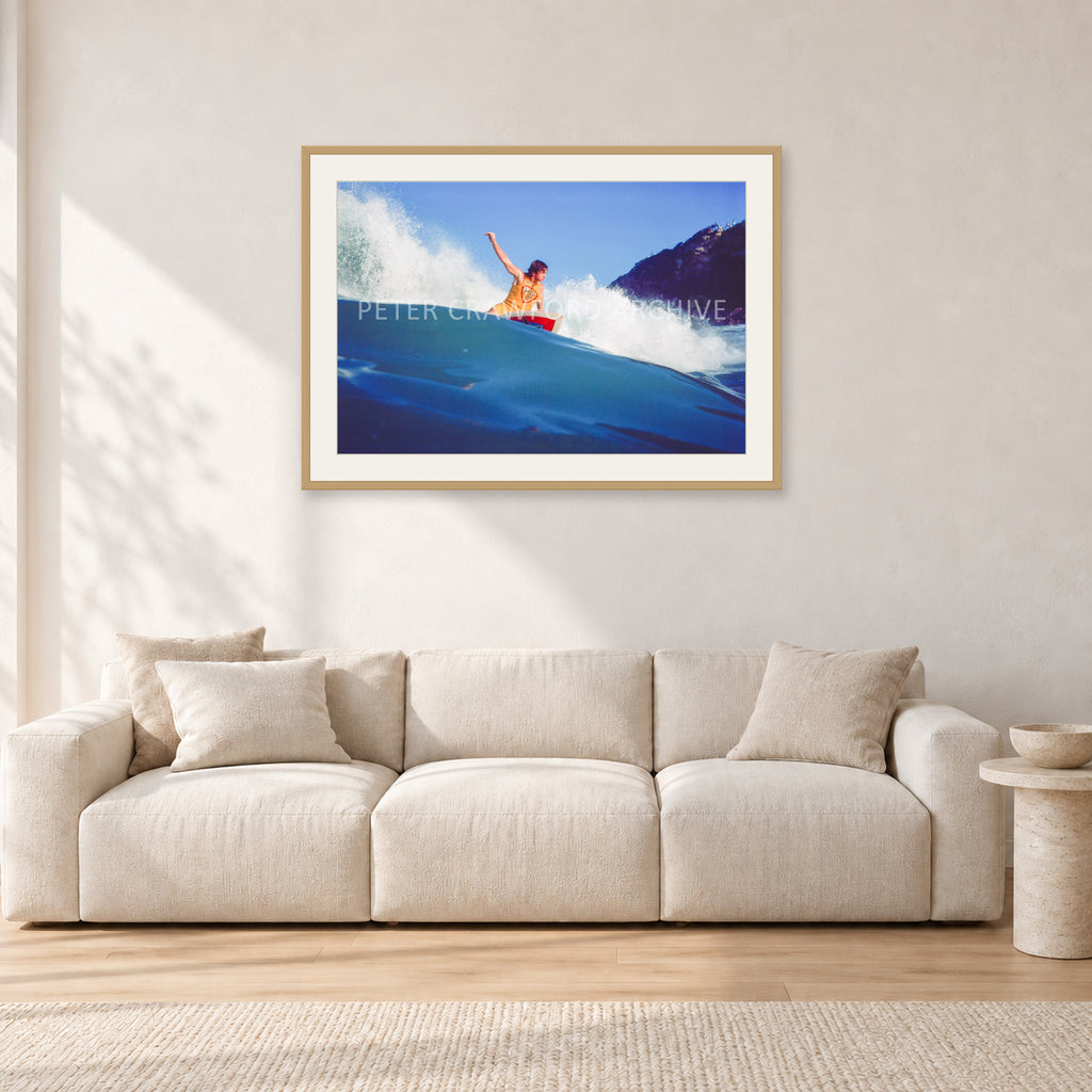 Mark Richards, Bells Beach 1979 by Peter Crawford — 90 × 60 cm, hayseed frame with white mat, shown in a light minimalist living room.
