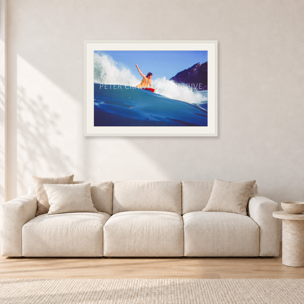 Mark Richards, Bells Beach 1979 by Peter Crawford — 90 × 60 cm, white frame with white mat, shown in a light minimalist living room.