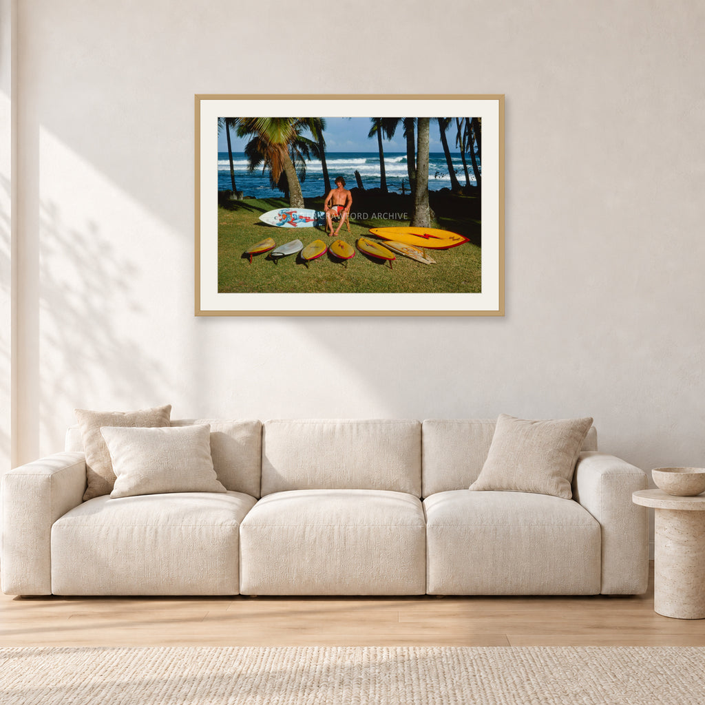 Mark Richards Hawaiian Quiver, North Shore 1976 by Peter Crawford — 90 × 60 cm, hayseed frame with white mat, shown in a light minimalist living room.