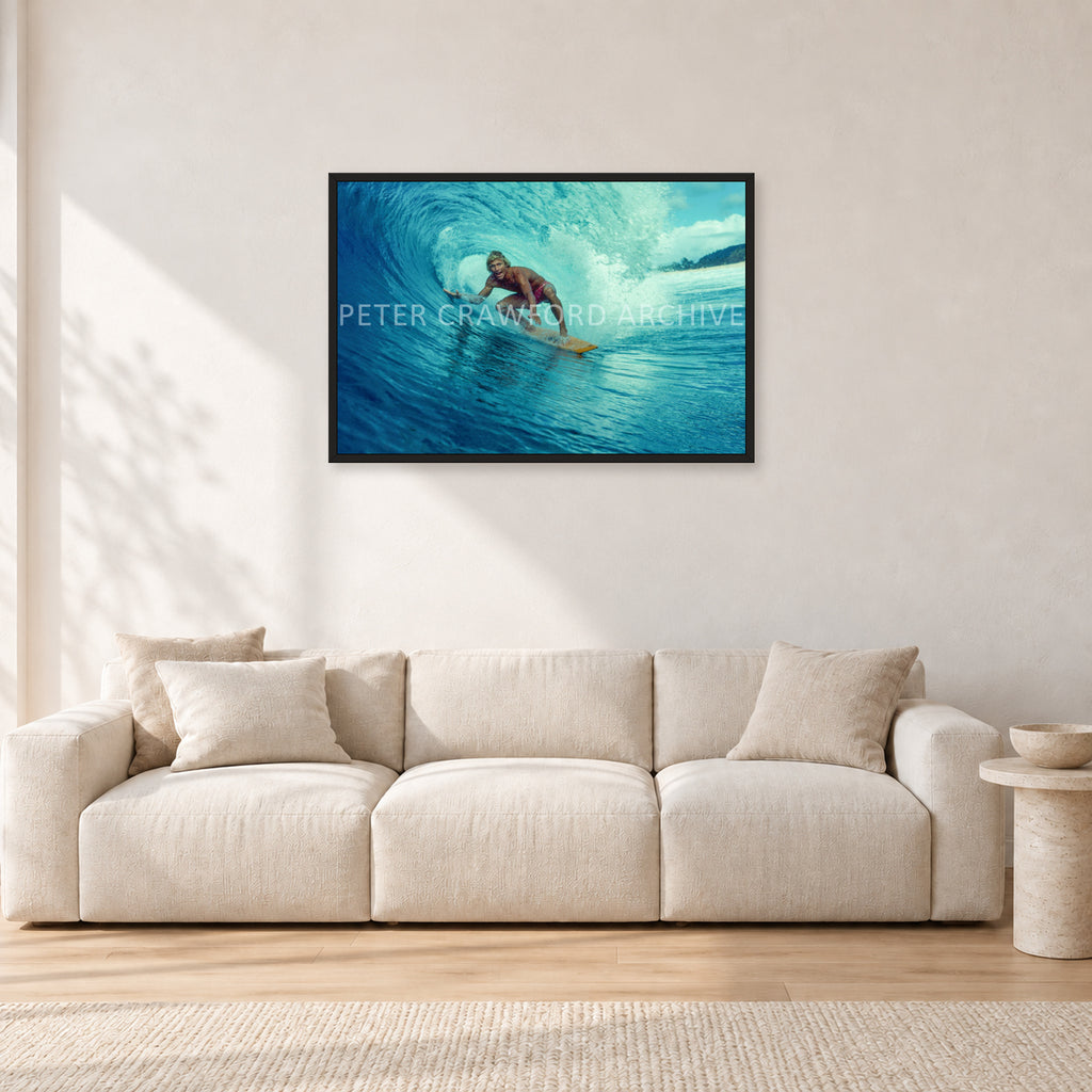 North Shore Tube Ride, Hawaii 1970s by Peter Crawford — 90 × 60 cm, black frame, shown in a light minimalist living room.