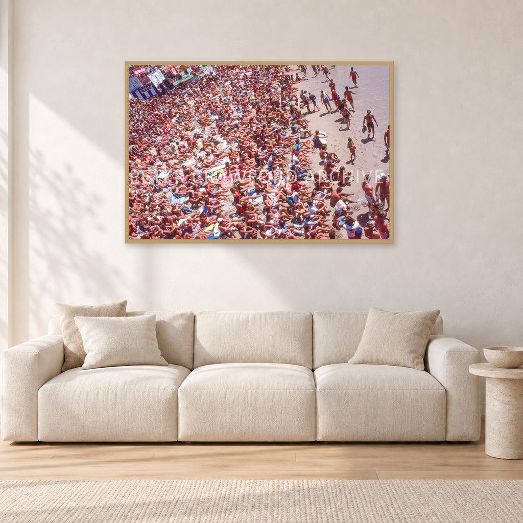Op Pro Crowd 85 by Peter Crawford — 120 × 80 cm, hayseed frame, shown in a light minimalist living room.