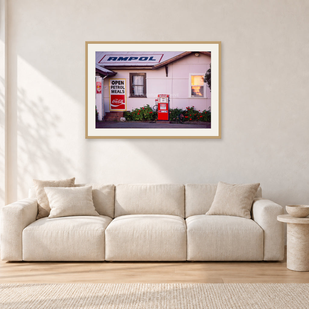 Seventies Petrol Station, 1970 by Peter Crawford — 90 × 60 cm, hayseed frame with white mat, shown in a light minimalist living room.