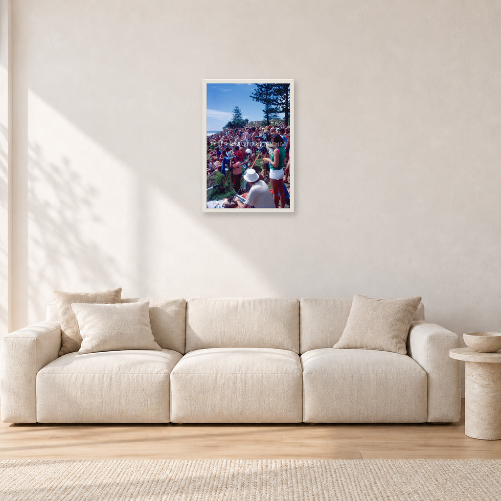 Stubbies Camera Crowd 78 Steve O'Ferral by Peter Crawford — 40 × 60 cm, white frame, shown in a light minimalist living room.