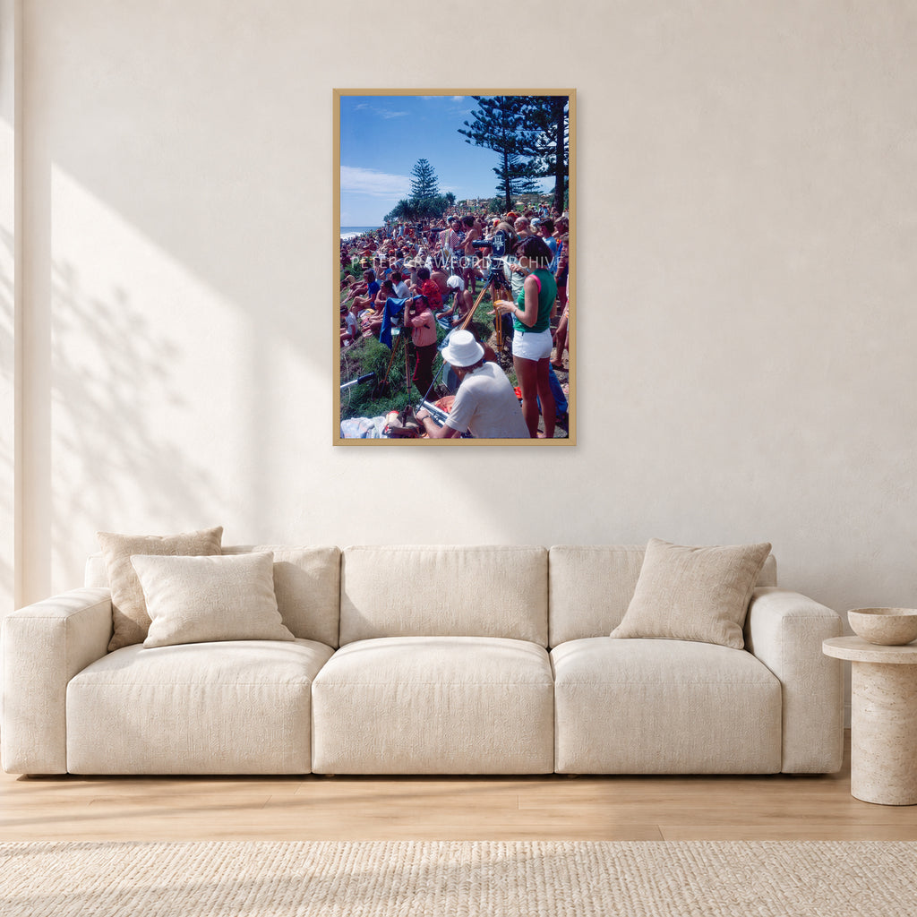 Stubbies Camera Crowd 78 Steve O'Ferral by Peter Crawford — 60 × 90 cm, hayseed frame, shown in a light minimalist living room.