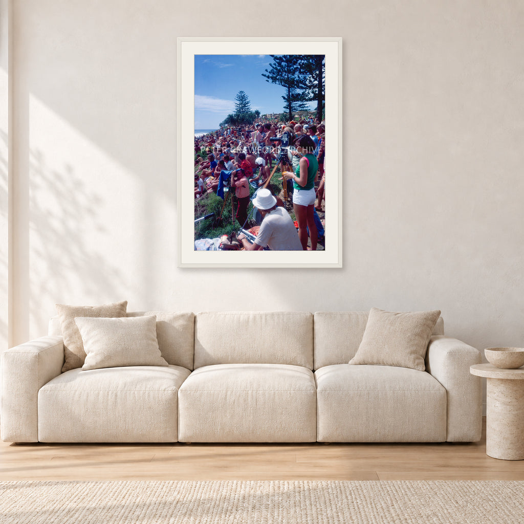 Stubbies Camera Crowd 78 Steve O'Ferral by Peter Crawford — 60 × 90 cm, white frame with white mat, shown in a light minimalist living room.
