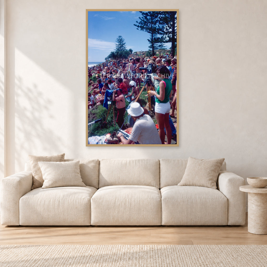 Stubbies Camera Crowd 78 Steve O'Ferral by Peter Crawford — 80 × 120 cm, hayseed frame, shown in a light minimalist living room.