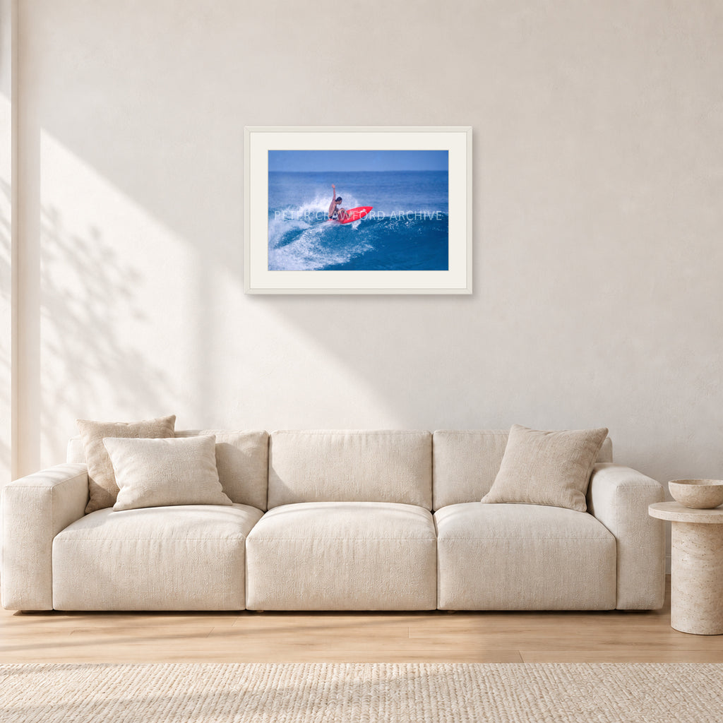 Sunset Beach, Hawaii by Peter Crawford — 60 × 40 cm, white frame with white mat, shown in a light minimalist living room.
