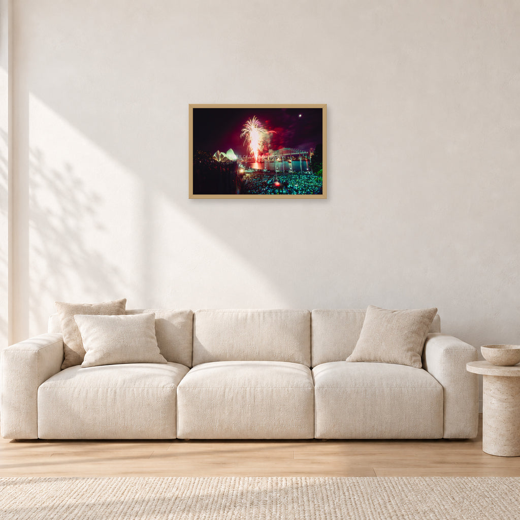 Tom Carroll and Aaron Chang, Waimea 1985 by Peter Crawford — 60 × 40 cm, hayseed frame, shown in a light minimalist living room.