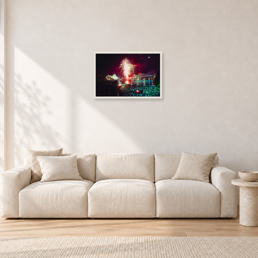 Tom Carroll and Aaron Chang, Waimea 1985 by Peter Crawford — 60 × 40 cm, white frame, shown in a light minimalist living room.