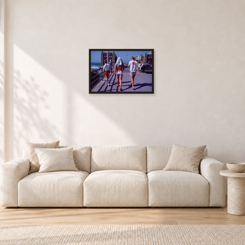 Tom Carroll, Mike Newling and Simon Anderson, Huntington 1984 by Peter Crawford — 60 × 40 cm, black frame, shown in a light minimalist living room.