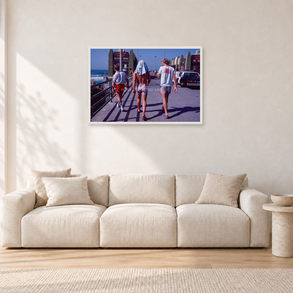 Tom Carroll, Mike Newling and Simon Anderson, Huntington 1984 by Peter Crawford — 90 × 60 cm, white frame, shown in a light minimalist living room.