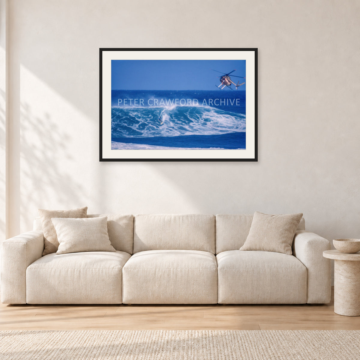 Tom Carroll, Sunset Beach Aerial by Peter Crawford — 90 × 60 cm, black frame with white mat, shown in a light minimalist living room.