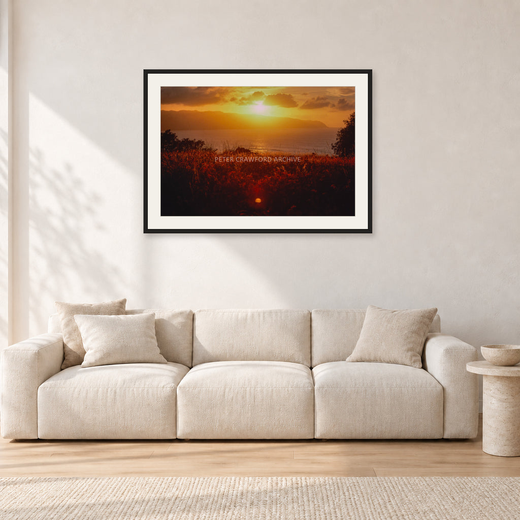 Waimea Dusk by Peter Crawford — 90 × 60 cm, black frame with white mat, shown in a light minimalist living room.